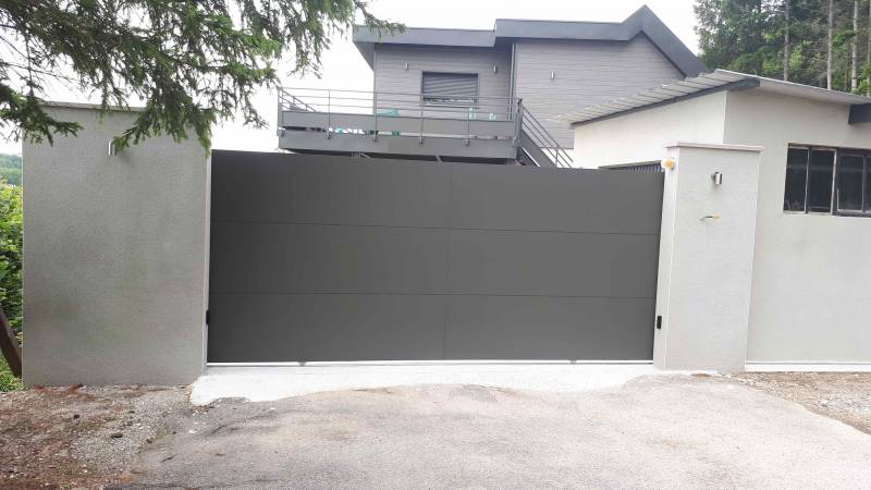Installer un portail coulissant plein motorisé en aluminium couleur gris terre 7022 à Eslettes près de Montville 76 et une porte d’entrée EURADIF en aluminium