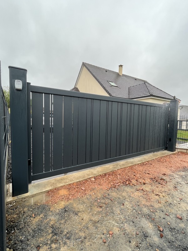 Remplacement d’un portail traditionnel par un portail coulissant motorisé en aluminium gris anthracite avec création de longrine à La Vaupalière près de Rouen (76)